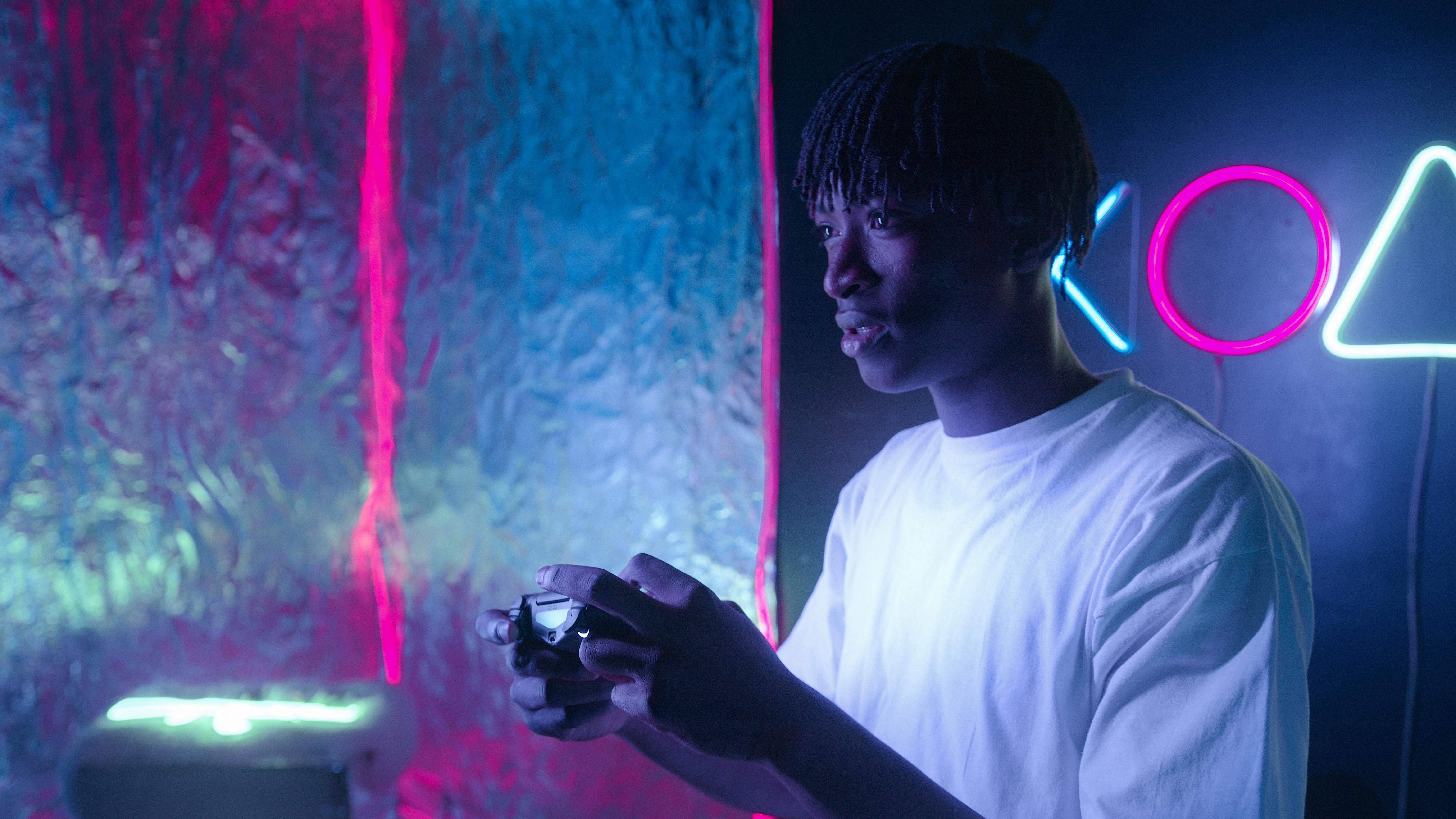 Young man focused on video gaming with vibrant neon lights illuminating the scene.